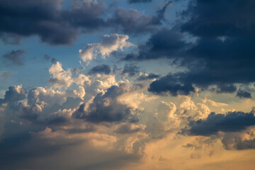 Cloudy sky at sunset. Cumulus clouds painted in golden and blue colors. Dramatic heavenly...
