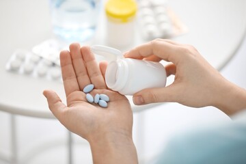 Woman taking pills at home, closeup