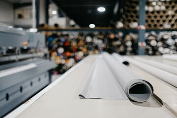 Selective focus shot of white rolls of textile for roller blinds in a factory