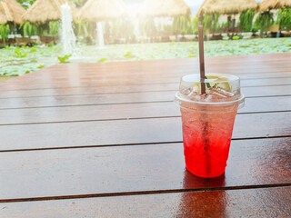 Lychee juice mixed with red rose tea and bright natural lotus pond background.