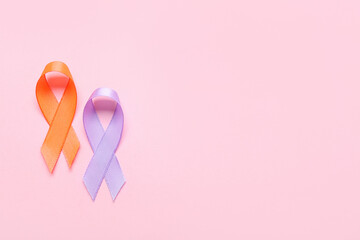 Orange and lilac ribbons on color background. Cancer awareness concept