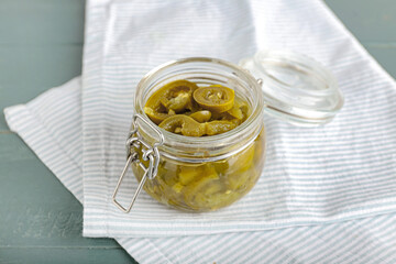 Glass jar with canned jalapeno on color wooden background