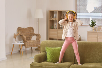Little girl in headphones listening to music at home