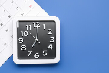 Stylish clock and calendar on color background