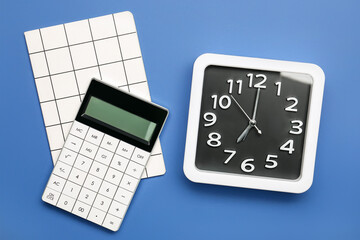 Stylish clock with calculator and notebook on color background