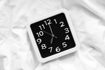 Stylish clock on bed in morning