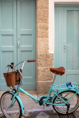 a bicycle with a wicker basket in front of the door of a house in Polignano a Mare