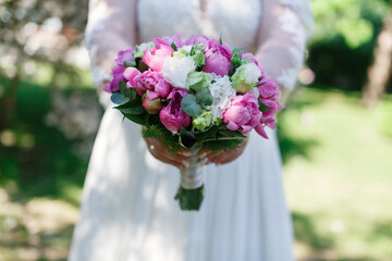 bride in white dress holds a wedding bouquet of pink flowers close up. festive  bouquet  in woman hands.
stylish  bridal bouquet . wedding decor. wedding day