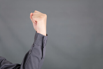 Hand making a fist in front of gray background