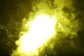 Artificial magic yellow light illuminates smoke on dark background