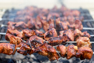 Large pieces of meat on a skewer are cooked on the grill