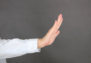 Hand outstretched in rejection gesture in front of gray background