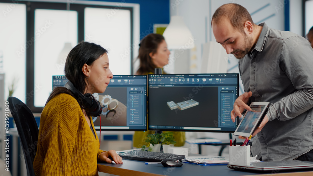 Wall mural industrial designer holding tablet discussing with woman engineer while working in cad program, desi