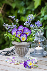 Dekoration mit Hornveilchen-Strauß und Windlicht