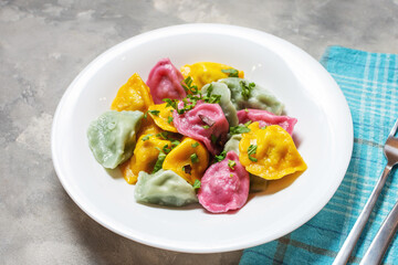 Multi colored dumplings from color dough stuffed with meat on concrete background