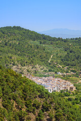 Fototapeta na wymiar Idyllic white Spanish city in countryside landscape surrounded by a green forest. Aín, Comunidad Valenciana, Spain