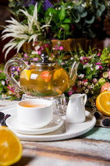 green tea with berries in a glass kettle and white utensils