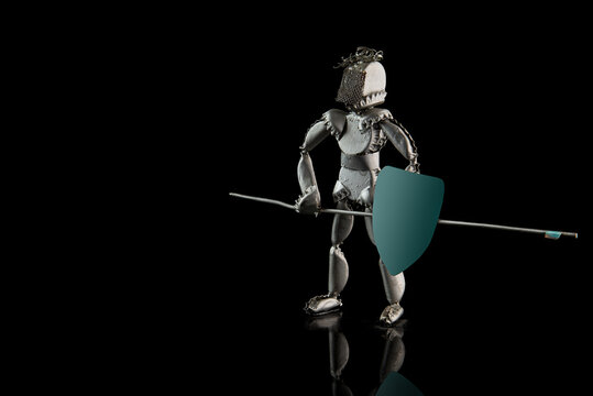 Knight with a blue shield and a spear. Old craft from metal bottle caps isolated on a black background.