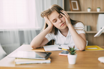 The exhausted schoolgirl is tired of doing homework, from studying at home, preparing for exams. Home education, home education