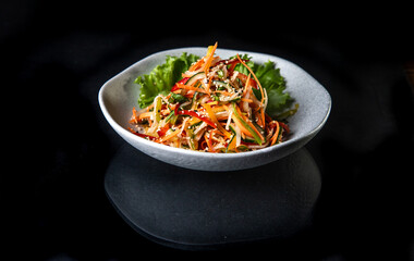 Japanese salad in a white plate on a black background