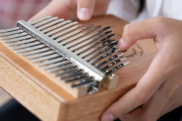 Hand of an Asian girl playing a wooden Kalimba instrument