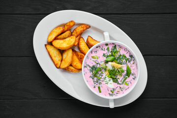 Overhead view of cold beet soup with potato wedges