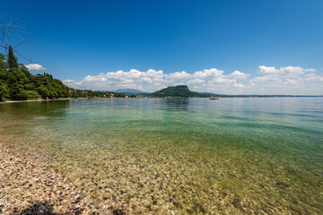 Beautiful beach on Lake Garda (Lago di Garda) in front of the small town of Garda. Headland of San...