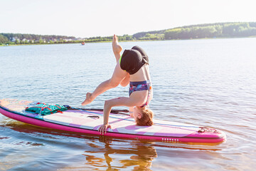 woman doing yoga on sup board at sunset. outdoor summer activity. Sup yoga. Social Distancing. copy...