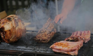 Grilled meat on the grill. Barbeque with smoke on grill. 
A man's hand makes a barbecue․
