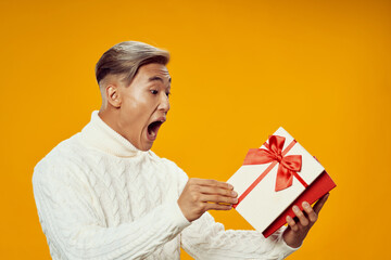 emotional man holding a gift holiday yellow background