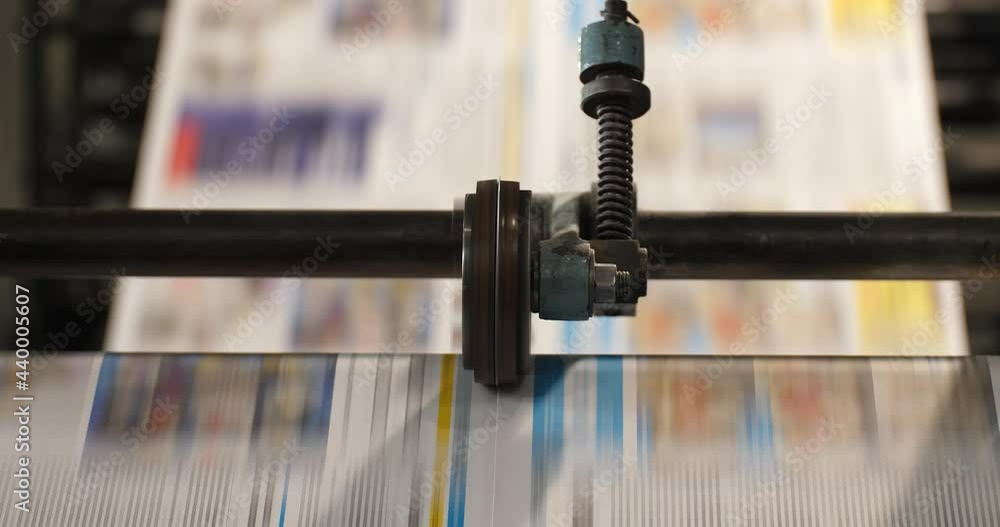 Poster newspaper runs through a roll machine parallel to the camera view with two layers of focus revealed 