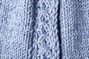 blue knitted product on knitting needles on a white background