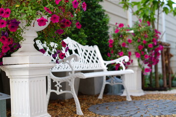 Fototapeta na wymiar white bench in the garden with red flower