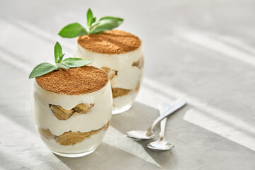 Classic dessert tiramisu in a glass on a table on a sunny day.