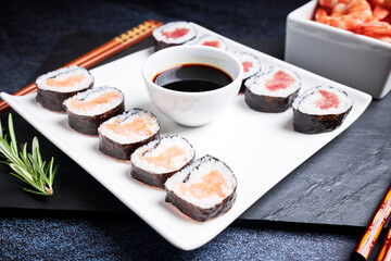 Plate with sushi, bowl of soy sauce and wooden chopsticks. Asian food. Healthy food concept