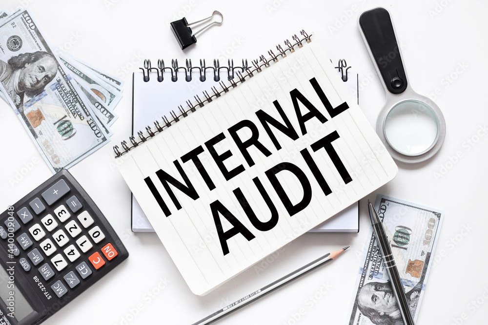 Poster internal audit. notebook on white workspace. near the notepad dollar bills and a calculator