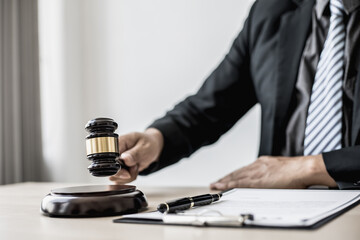 A lawyer or legal advisor holding a small hammer for a judge's table in court is about to pound on the podium to deliver a fair and legal verdict. The concept of correct and fair litigation.