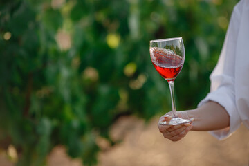 Vintner woman tasting red wine from a glass in a vineyard