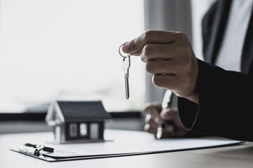 The salesperson holds the keys to hand to the customer on the day of handover of the house in the...