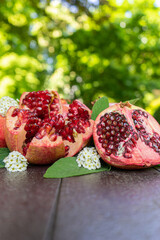 Cut Open Pomegranates on a Wooden Table Outside with White Flowers