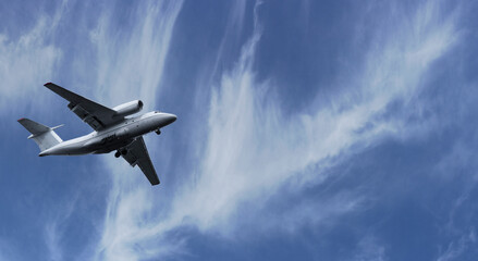 The plane took off into the sky. Airplane flight on a background of blue cloudy sky on a clear sunny day.