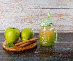 Green apples and glass with apple juice on wooden background