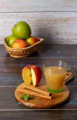 Basket of green, red apples and cup with cold apple juice on wooden background