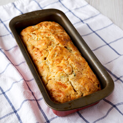 Homemade Cheesy Bread Loaf on a white wooden background, low angle view.