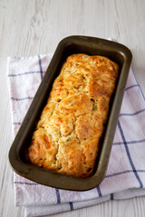 Homemade Cheesy Bread Loaf on a white wooden surface, side view.