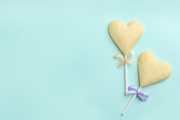 Chocolate heart shaped lollipops on turquoise background, flat lay. Space for text