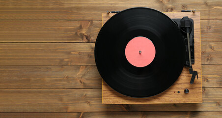 Turntable with vinyl record on wooden background, top view