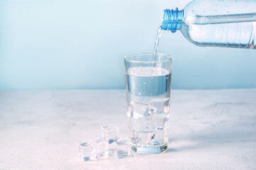 Water pours from a bottle into a glass with ice