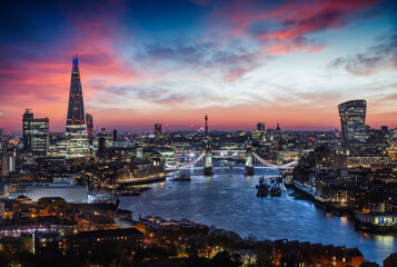 Elevated, panoramic view to the lit skyline of London, United Kingdom, just after sunset with Tower...
