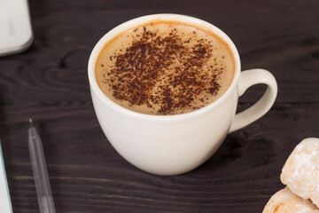 Workplace mockup with a cup of cappuccino coffee on a wooden dark table with a laptop and notepad